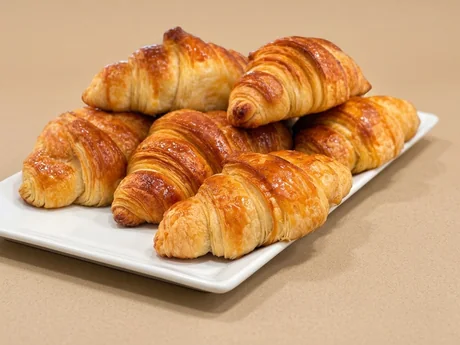 Croissants recién horneados y brillantes en bandeja